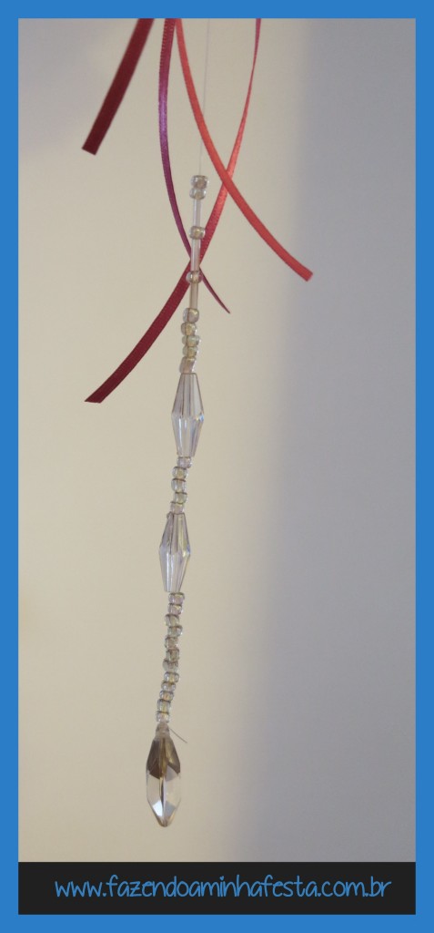 Ao colar o fio de nylon, cole de forma que o pendente de miçanga inicie onde terminam as fitas de cetim. deixe um pedaço grande do feio de cetim para cima, para pendurar o pendente no teto.